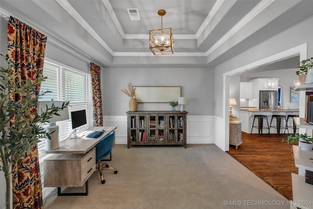 home office featuring a raised ceiling, a chandelier, carpet flooring, wainscoting, and crown molding