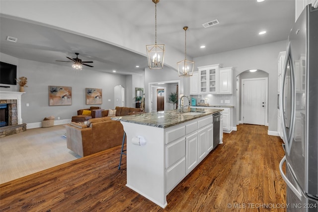 kitchen featuring stainless steel appliances, arched walkways, a sink, a fireplace, and open floor plan