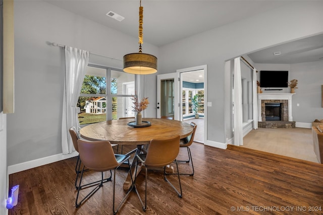 dining area with healthy amount of natural light, a stone fireplace, and wood finished floors