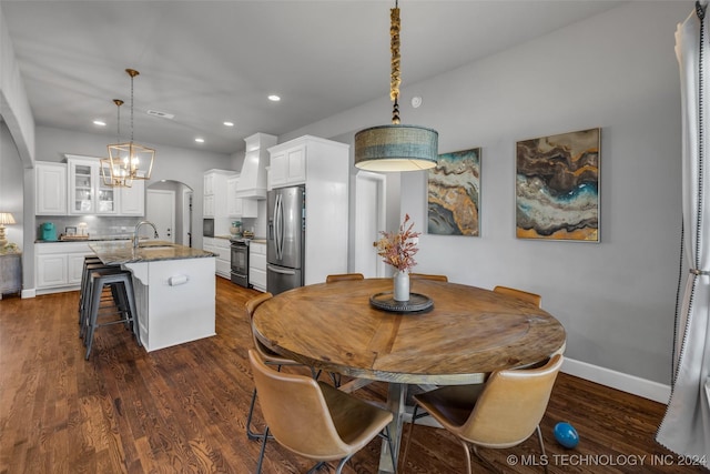 dining room with a chandelier, arched walkways, recessed lighting, dark wood-style flooring, and baseboards