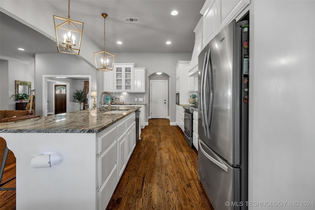 kitchen featuring stainless steel appliances, a sink, a chandelier, arched walkways, and dark wood-style floors