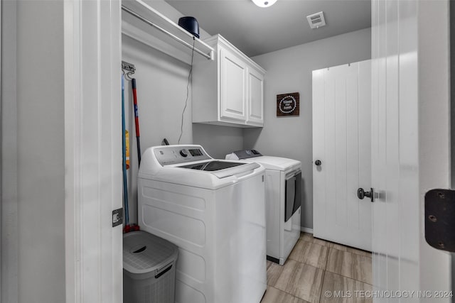 clothes washing area with cabinet space and independent washer and dryer