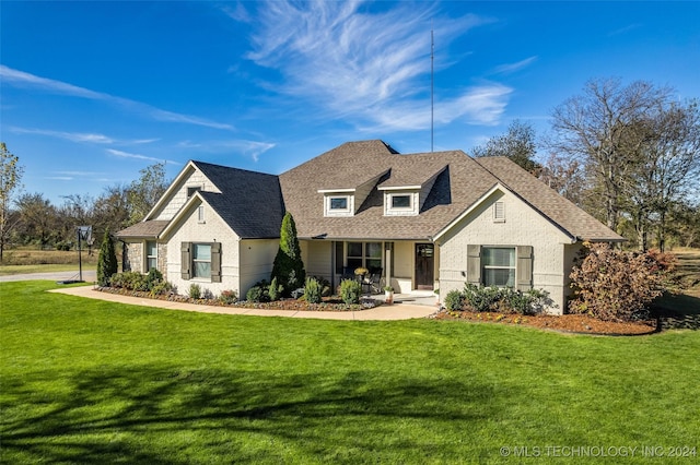 view of front of house with a shingled roof, a porch, and a front lawn