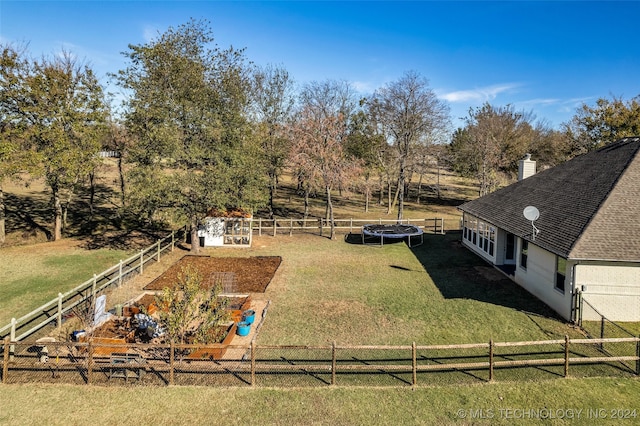 view of yard featuring a rural view, a storage unit, and a trampoline