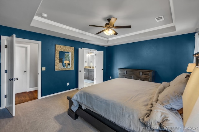 carpeted bedroom featuring ensuite bath, ceiling fan, a tray ceiling, and crown molding