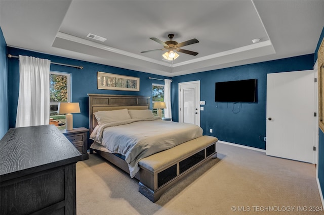 carpeted bedroom featuring ceiling fan, a tray ceiling, and multiple windows