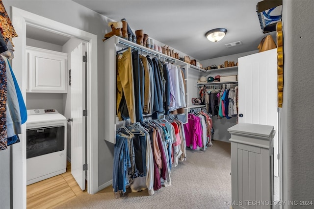 spacious closet with washer / clothes dryer and light carpet