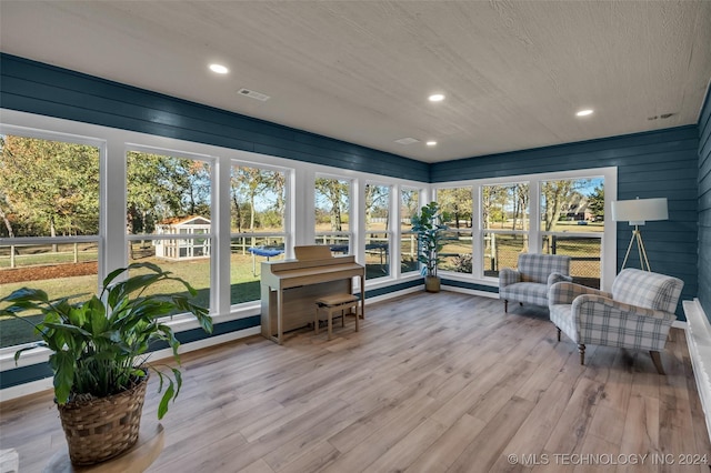 sunroom / solarium with wood finished floors, recessed lighting, plenty of natural light, and a wooden deck