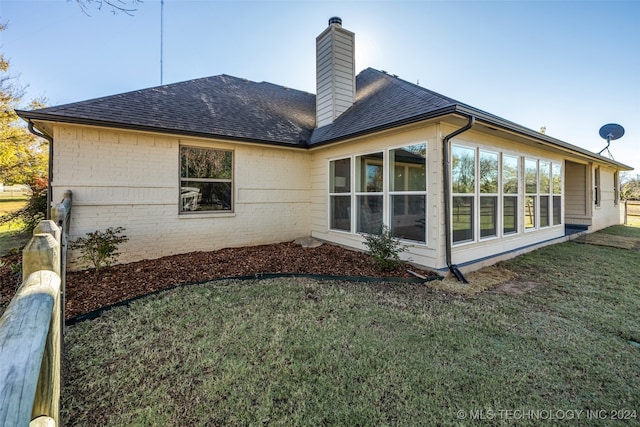 rear view of property with a lawn and a sunroom