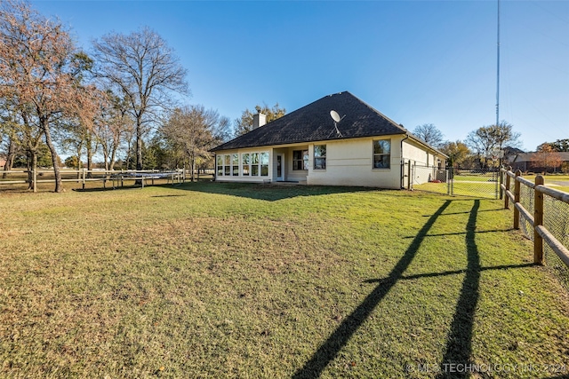 rear view of property featuring a lawn and a rural view