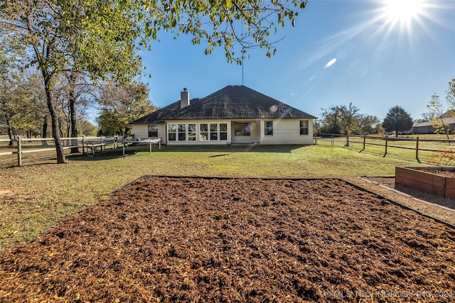 back of property featuring a rural view and a lawn