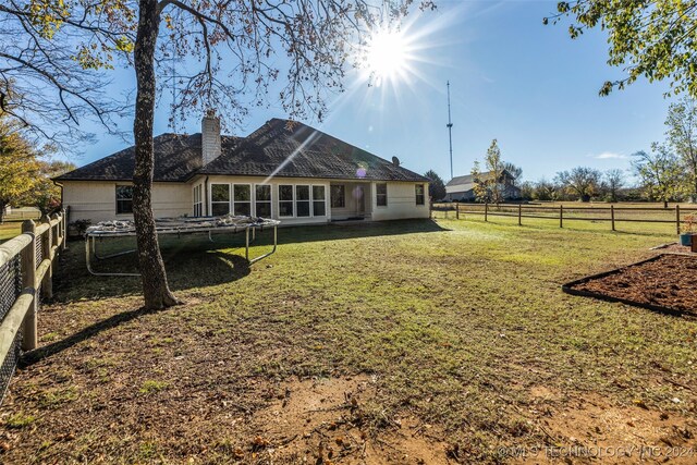 back of house featuring a yard, a rural view, and a trampoline