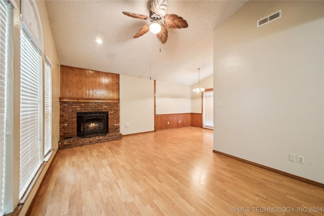 unfurnished living room with a fireplace, light hardwood / wood-style flooring, wood walls, and a textured ceiling