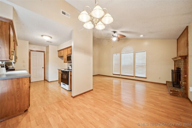 kitchen with white range with gas stovetop, sink, light hardwood / wood-style floors, lofted ceiling, and ceiling fan with notable chandelier