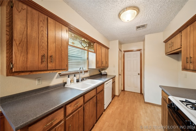 kitchen with white appliances, light hardwood / wood-style floors, a textured ceiling, and sink