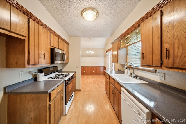 kitchen with a textured ceiling, a notable chandelier, sink, light hardwood / wood-style floors, and white appliances