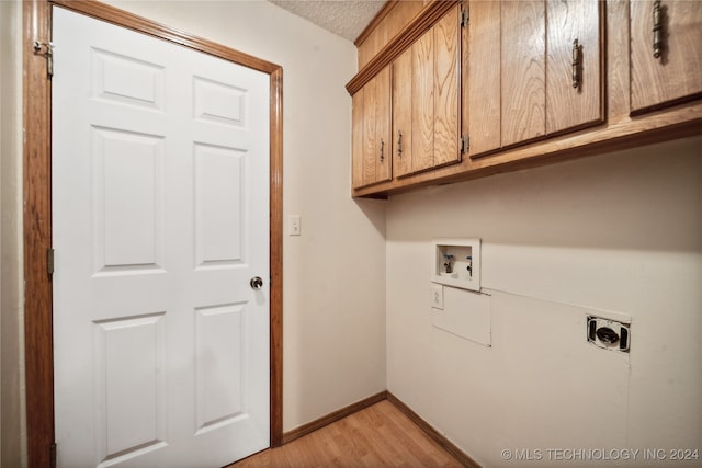 laundry area featuring light hardwood / wood-style floors, electric dryer hookup, cabinets, a textured ceiling, and washer hookup