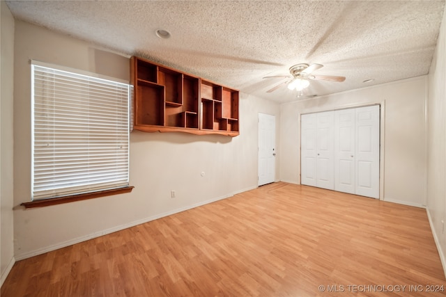 unfurnished bedroom featuring ceiling fan, a textured ceiling, a closet, and light wood-type flooring