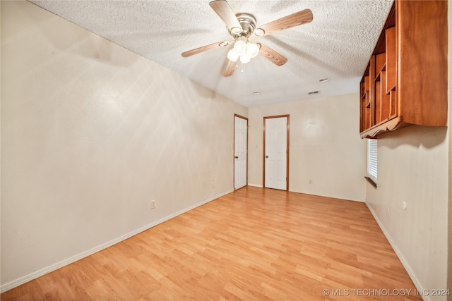 empty room featuring light wood-type flooring, a textured ceiling, and ceiling fan