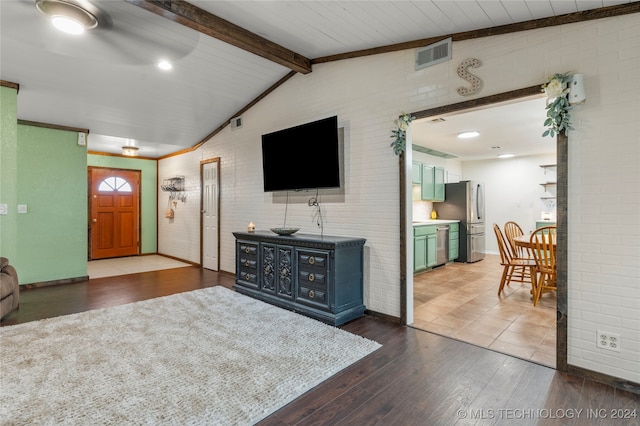 living room featuring dark hardwood / wood-style floors, lofted ceiling with beams, brick wall, and ceiling fan