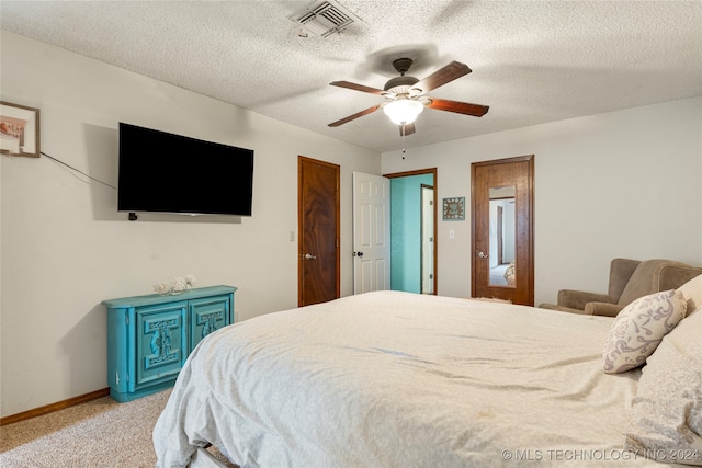 carpeted bedroom with ceiling fan and a textured ceiling