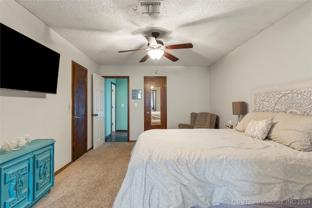 bedroom featuring ceiling fan, light colored carpet, and a textured ceiling