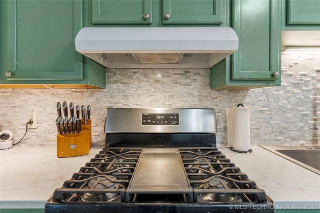 kitchen featuring stainless steel range with gas stovetop, light stone counters, green cabinetry, and exhaust hood