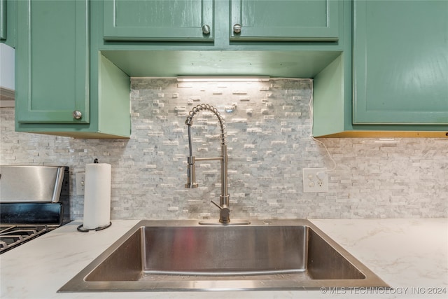 kitchen with decorative backsplash, green cabinets, and sink