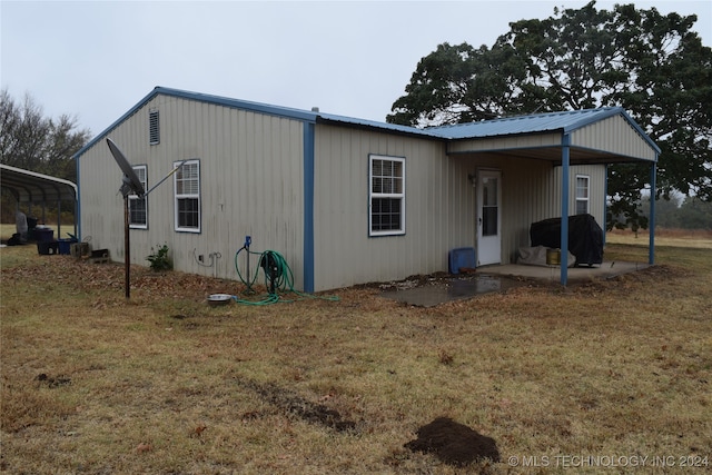 rear view of property with a lawn and a carport