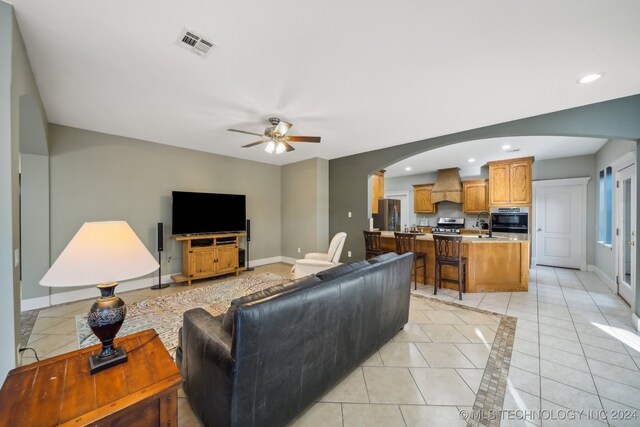 living room featuring light tile patterned floors, ceiling fan, and sink