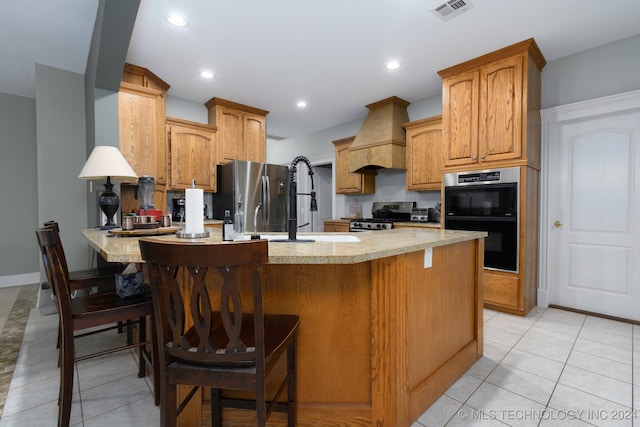 kitchen with premium range hood, light stone countertops, a kitchen bar, and appliances with stainless steel finishes