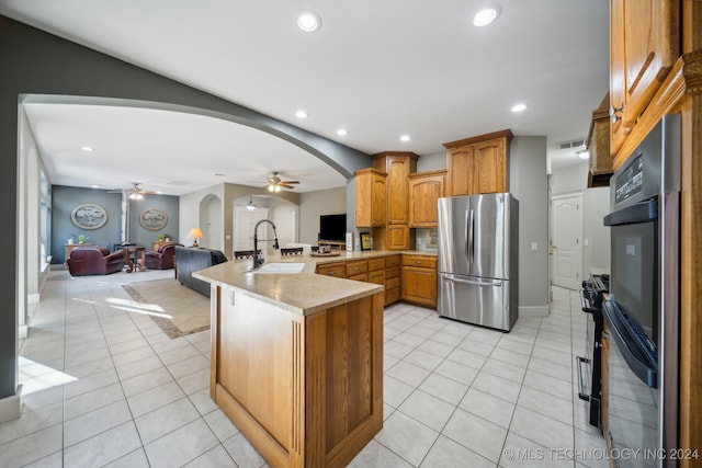 kitchen with kitchen peninsula, stainless steel fridge, light tile patterned floors, and sink