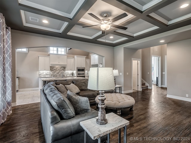 living room featuring beamed ceiling, ornamental molding, ceiling fan, coffered ceiling, and dark hardwood / wood-style flooring