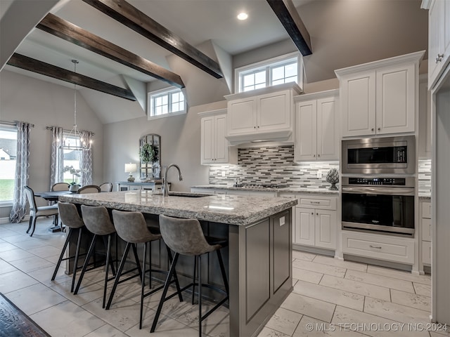 kitchen with a wealth of natural light, a center island with sink, sink, and appliances with stainless steel finishes