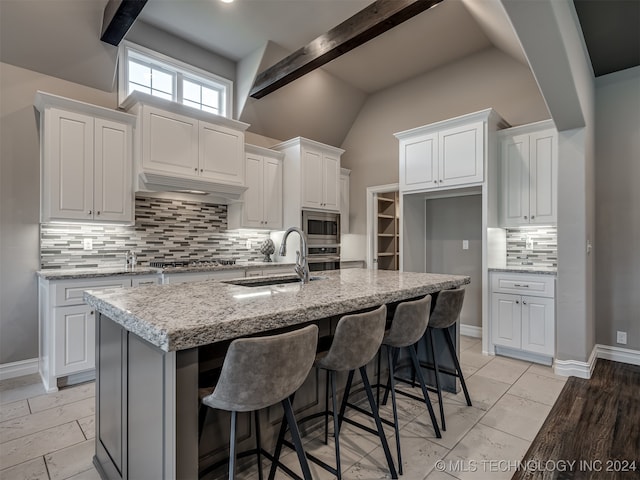 kitchen featuring stainless steel appliances, a center island with sink, sink, and white cabinetry