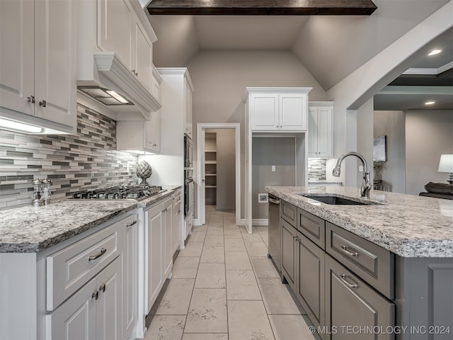 kitchen with white cabinetry, sink, backsplash, and light stone countertops