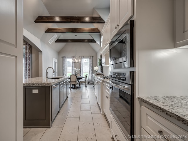 kitchen with stainless steel appliances, vaulted ceiling with beams, white cabinets, sink, and a chandelier