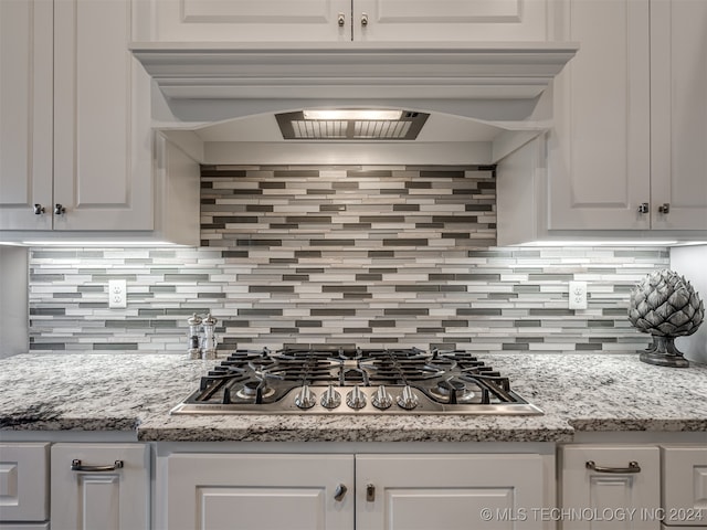 kitchen with white cabinetry, stainless steel gas stovetop, and backsplash