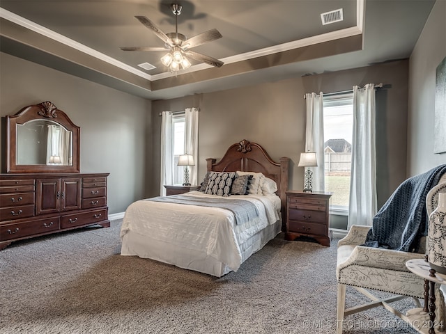 carpeted bedroom featuring crown molding, ceiling fan, and a raised ceiling