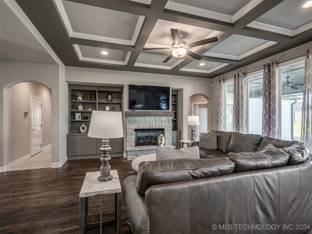 living room with dark hardwood / wood-style floors, beam ceiling, a stone fireplace, coffered ceiling, and built in features