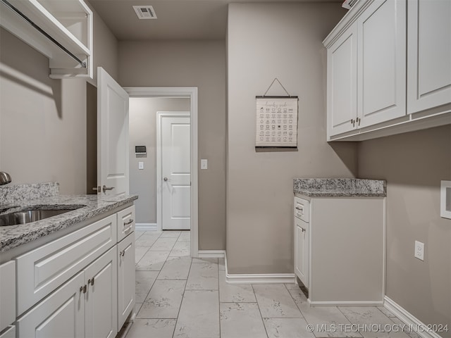 clothes washing area featuring cabinets and sink