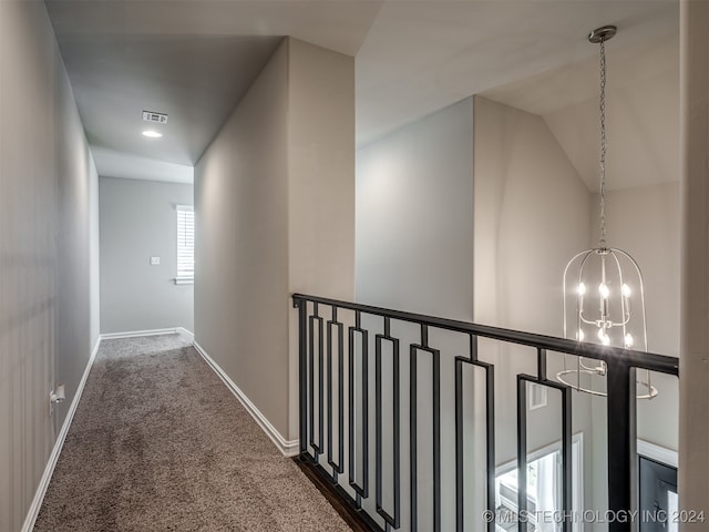 corridor featuring a chandelier, lofted ceiling, and dark carpet