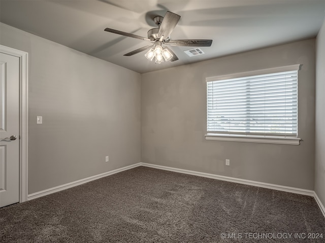 empty room with ceiling fan and dark carpet