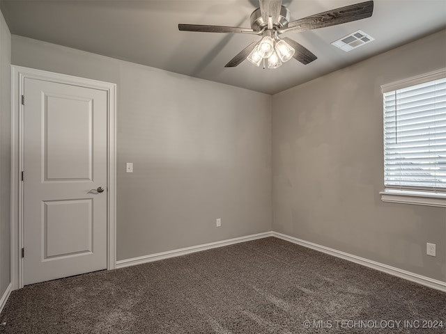 empty room with ceiling fan and dark carpet