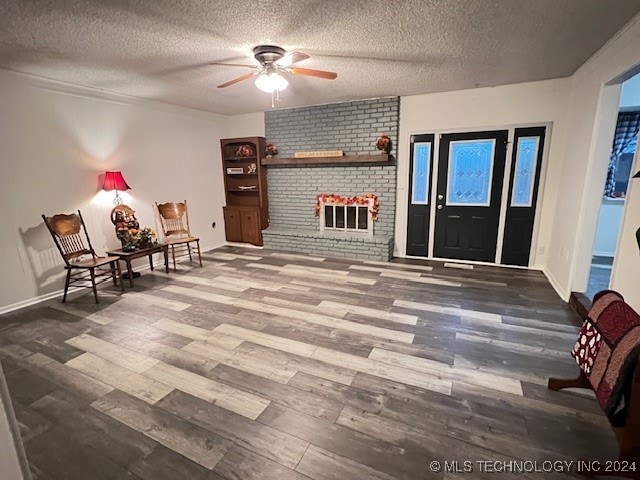 living area with hardwood / wood-style floors, a fireplace, a textured ceiling, and ceiling fan