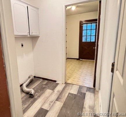 clothes washing area featuring cabinets, electric dryer hookup, and light hardwood / wood-style flooring