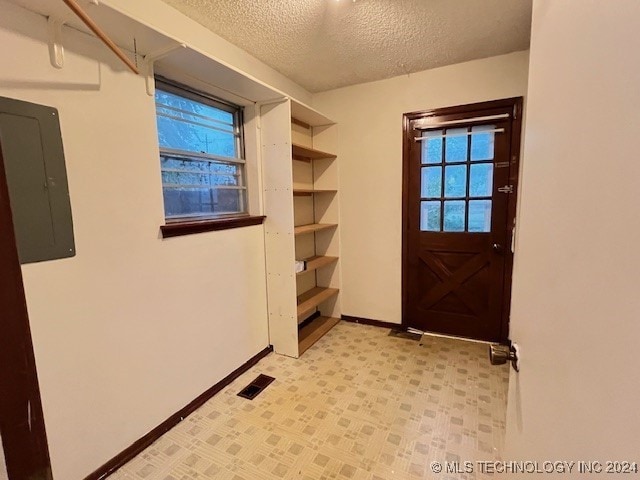 doorway featuring electric panel and a textured ceiling