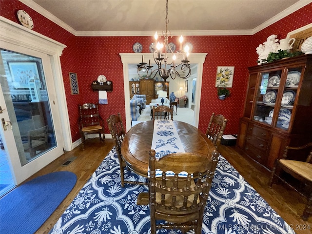 dining area featuring ornamental molding, dark wood-type flooring, and an inviting chandelier