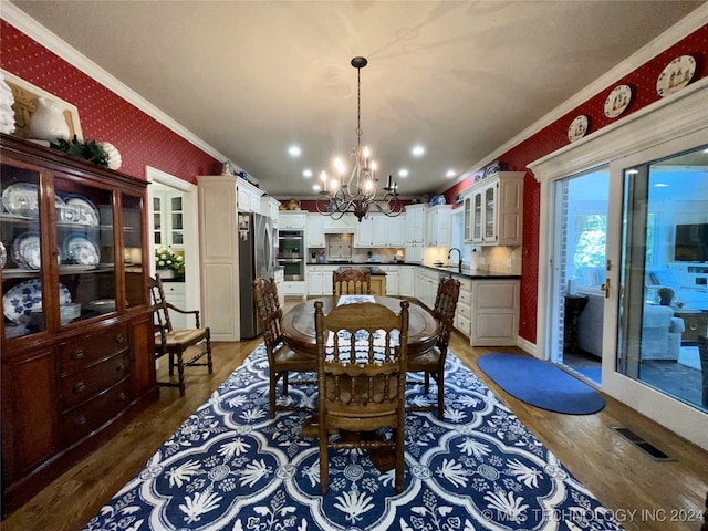 dining area with dark hardwood / wood-style floors, sink, crown molding, and a notable chandelier