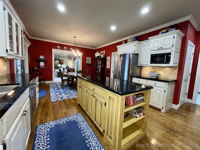 kitchen with hardwood / wood-style floors, stainless steel refrigerator, and white cabinets